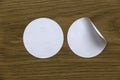 Blank white round stickers straightened and with folded corner on wooden background Royalty Free Stock Photo