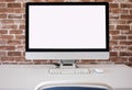 Blank white screen computer in minimal office room, copy space. Brick wall background Royalty Free Stock Photo