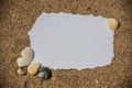 Blank white sheet of paper on white sand with seashells and stones. Message by the sea, romance, valentine's Royalty Free Stock Photo