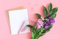 Blank white sheet on spiral golden notepad with paper clip heart and ring and bouquet of flowers on pink background. Concept Royalty Free Stock Photo