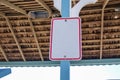 Blank white sign with red boarder attached to a blue post with the inside of the wooden ceiling as a background Royalty Free Stock Photo