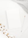 Blank white spiral notebook with pencil, cotton flowers and grey stripe fabric on white bed sheet. Royalty Free Stock Photo