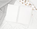 Blank white spiral notebook with pencil, cotton flowers, grey stripe fabric and wooden letter on white bed sheet. Royalty Free Stock Photo