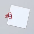 Blank white square note paper held by a red binder clip on a gray surface Royalty Free Stock Photo
