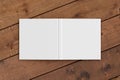 Blank white square open and upside down book cover on wooden boards isolated with clipping path around cover. Royalty Free Stock Photo