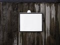 Blank white square sign on a wooden and frozen wall.