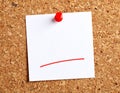 A blank white sticky note with deep red bold handwriting pinned to a corkboard square Royalty Free Stock Photo