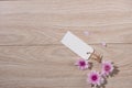 Blank white tag paper with color flowers on wooden background. T Royalty Free Stock Photo