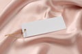 Blank white tag on pink silky fabric, closeup. Space or text