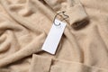 Blank white tags on beige sweater, top view. Space for text Royalty Free Stock Photo