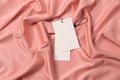 Blank white tags on pink silky fabric, top view. Space for text Royalty Free Stock Photo