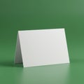 A blank white tent card stands on a smooth, green surface, set against a matching gre Royalty Free Stock Photo