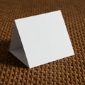 A blank white tent card stands upright on a woven, brown textured surface. The card Royalty Free Stock Photo