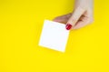 Blank white To Do List Sticker in woman hand. Close up of reminder note paper on the yellow background. Copy space. Minimalism, Royalty Free Stock Photo
