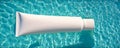 Blank white tube mockup on surface of clean blue transparent water. Empty cosmetic plastic packaging for cosmetic presentation. Royalty Free Stock Photo