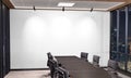 Blank white wall Mockup in dark modern office with windows and spotlights. Empty company meeting room 3D rendering Royalty Free Stock Photo