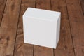 Blank white wide square box with closed hinged flap lid on dark wooden background. Clipping path around box mock up. Royalty Free Stock Photo