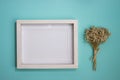 A blank white wooden frame with flower bouquet over the mint background. Royalty Free Stock Photo