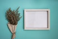 A blank white wooden frame with flower bouquet over the mint background. Royalty Free Stock Photo