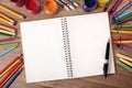 Blank white writing book open on school desk, pen, pencils, copy space