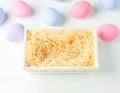 Blank wooden basket with wood wool on white background with pastel ester eggs