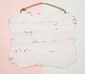 Blank wooden carved hanging on a blue and pink background