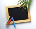 Blank Wooden Frame Blackboard with Colorful Chalk and Palm Leaf