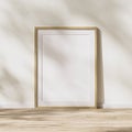 Blank wooden frame with mat mock up, wooden poster frame on wooden floor with sunlight with leaves shadow on white wall, 3d