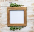 A blank wooden frame on white distressed wooden board background and green succulent-style leaves - picture frame mockup Royalty Free Stock Photo