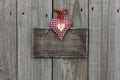 Blank wooden sign with red gingham and gold hearts hanging on wood background