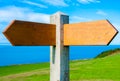 Blank wooden signpost with two arrows over clear blue sky with copy space Royalty Free Stock Photo