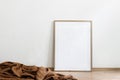 Blank wooden vertical picture frame mock-up on floor. Cinnamon linen plaid. White wall background. Empty copy space, no Royalty Free Stock Photo