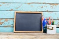 Blank writing slate by australian flag and desk organizer against wooden wall, copy space