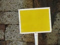 Yellow sign with empty space in front of stone wall