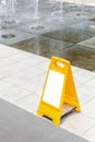 Blank yellow hazard sign alerts for a wet floor in fountain decoration area. Royalty Free Stock Photo