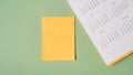 Blank yellow note paper with line and yearly calendar on green background with copy space