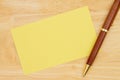 Blank yellow paper index card with pen on wood desk Royalty Free Stock Photo