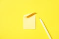 blank yellow paper note pad stick on vivid yellow background beside yellow pen Royalty Free Stock Photo