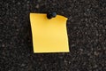 A blank yellow paper note pinned to a brown cork board Royalty Free Stock Photo