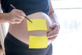 Blank yellow sticker notes on the pregnant woman`s belly. FAQ concept. Royalty Free Stock Photo