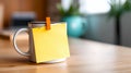A blank yellow sticky note is attached to a coffee mug which is kept on a table Royalty Free Stock Photo