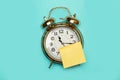 Blank yellow sticky note glued on the face of a bell alarm clock on a light blue background with copy space Royalty Free Stock Photo