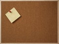 Blank yellow sticky note pinned on a cork bulletin board. Royalty Free Stock Photo