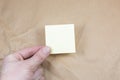 Blank yellow To Do List Sticker in Man hand. Close up of reminder note paper on kraft background. Copy space Royalty Free Stock Photo