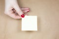 Blank yellow To Do List Sticker in woman hand. Close up of reminder note paper on kraft background. Copy space Royalty Free Stock Photo