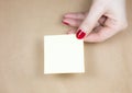 Blank yellow To Do List Sticker in woman hand. Close up of reminder note paper on kraft background. Copy space Royalty Free Stock Photo