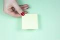 Blank yellow To Do List Sticker in woman hand. Close up of reminder note paper on the mint background. Copy space Royalty Free Stock Photo