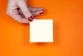 Blank yellow To Do List Sticker in woman hand. Close up of reminder note paper on the orange background. Copy space Royalty Free Stock Photo