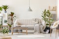 Blanket on beige settee under grey lamp in floral living room in
