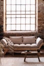 Blanket on beige settee and wooden table on carpet in loft living room interior with window Royalty Free Stock Photo